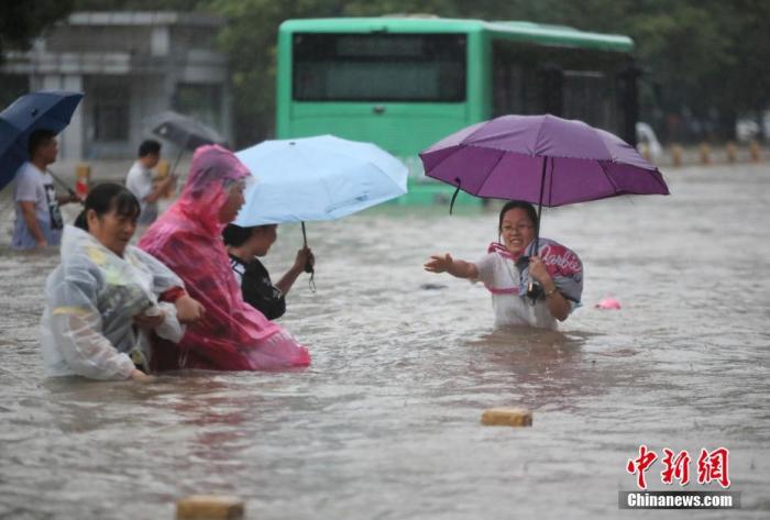 7月20日，鄭州遭遇強(qiáng)降雨，在經(jīng)三路、農(nóng)業(yè)路上，市民互相幫助走在齊腰深的積水里。 圖片來源：視覺中國
